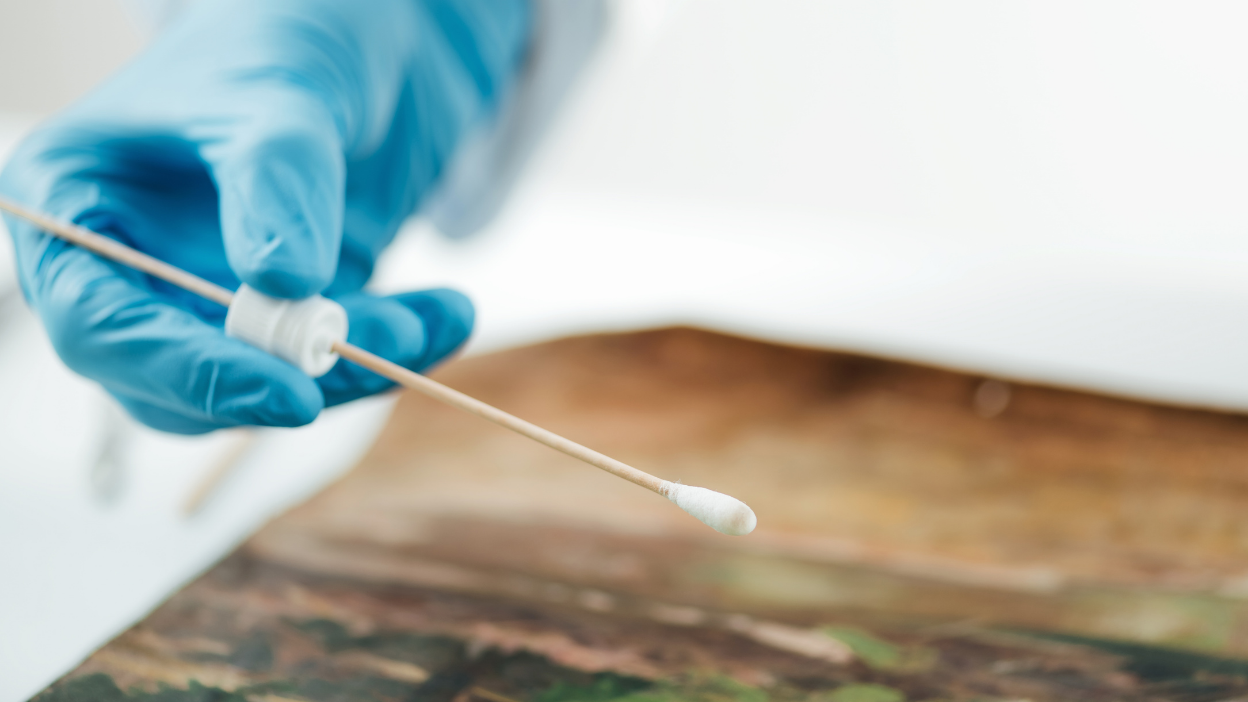 Conservator cleaning an oil painting